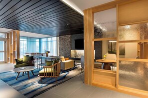 A modern living room with a dining area, large windows, a stone wall, and a fireplace. - Fairfield Inn & Suites by Marriott Shelby (Shelby)
