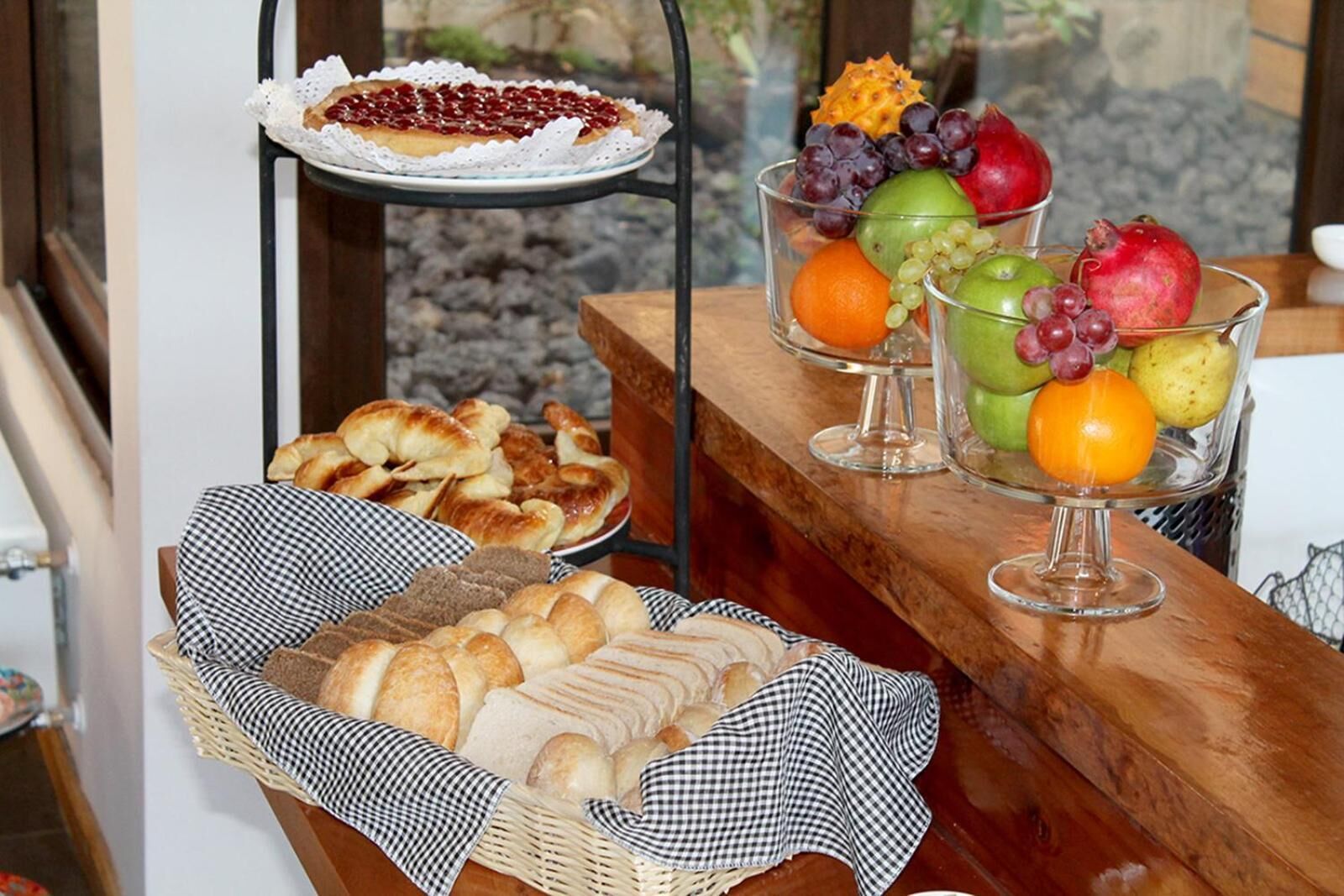 A breakfast buffet with pastries, bread, and a fruit display.