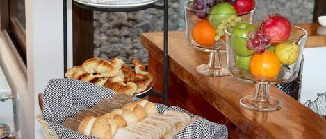 Un bufé de desayuno con pastelería, pan y una presentación de frutas.