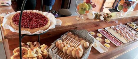 Un bufé con panes, pasteles y una tarta de cerezas.