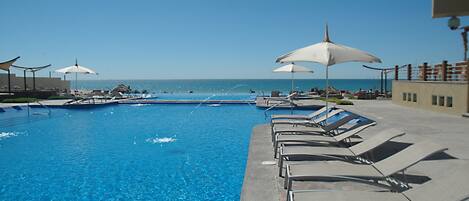 Outdoor pool, an infinity pool, pool umbrellas, pool loungers
