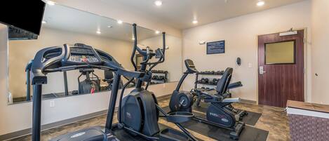 A gym with treadmills, elliptical machines, and a weight bench.