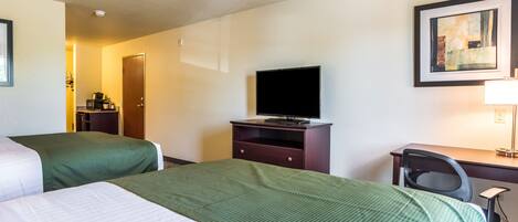 Een hotelkamer met twee bedden, een bureau, een stoel, een televisie en een ingelijst schilderij aan de muur.