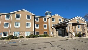 Un hotel de varios pisos con fachada de piedra, numerosas ventanas y un acceso cubierto.