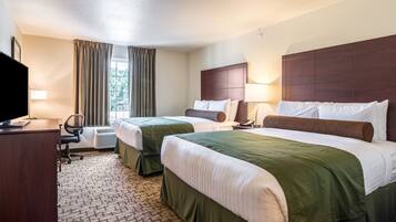 A hotel room with two beds, a desk, a chair, a TV, and a window with curtains.