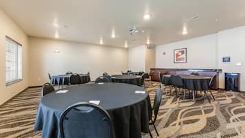 Una sala conferenze con tavoli rotondi, sedie, un proiettore e pavimento rivestito di moquette.