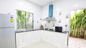 Eine Küche mit weißen Schränken, einem Edelstahl-Kühlschrank, einer Mikrowelle und einer blauen Dunstabzugshaube.