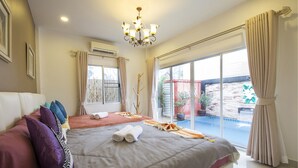 Ein Schlafzimmer mit zwei Betten, einer Kristallleuchter, einem großen Fenster mit Vorhängen und Blick auf Pool und Außenbereich.