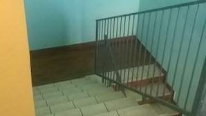 A staircase with a metal railing, wooden steps, and a light blue wall. - Oasi B&B (Porto Cesareo)