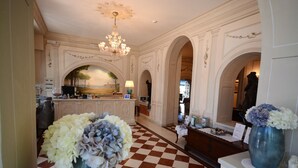 Eine Hotelhalle mit Schachbrettfußboden, einem Chandelier und einer Rezeption.