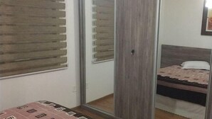 Une chambre à coucher avec un lit, une armoire et une fenêtre avec des stores.