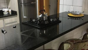Une cuisine avec un plan de travail noir, des appareils en acier inoxydable et un plateau jaune sur la droite.