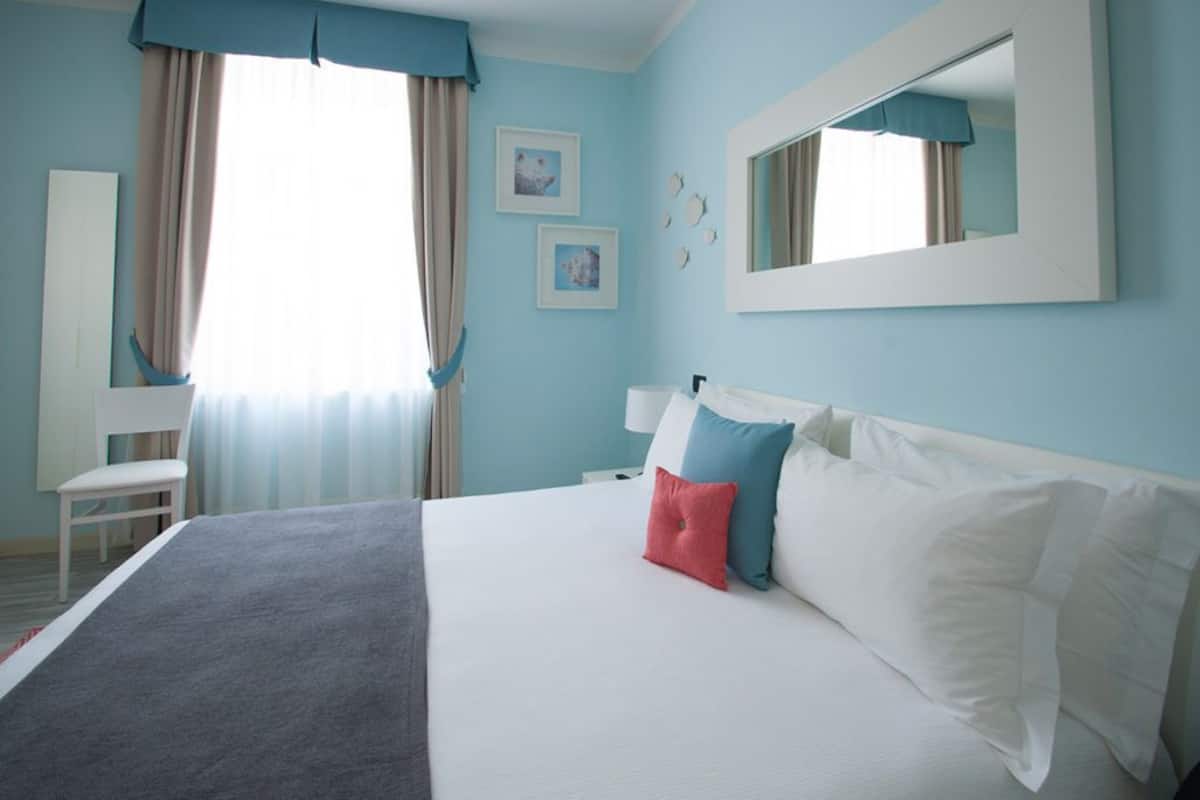 A bedroom with a bed, a chair, a dresser, and a mirror.