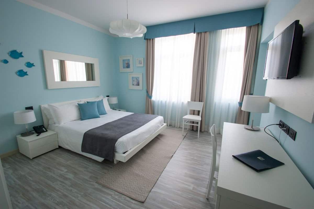 A modern bedroom with a bed, bedside tables, a desk, and a TV.