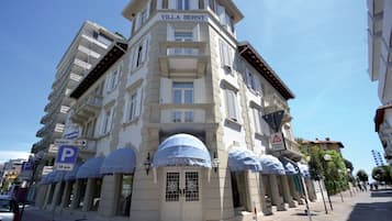 Un hotel a più piani, chiamato "Villa Bernt", in stile architettonico classico, con un ingresso ben visibile dotato di tenda, numerosi balconi e un cartello che indica un’area di parcheggio con limite di 30 minuti.