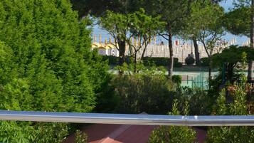 Una vista di un parco con alberi, un campo da tennis e una distesa d'acqua sullo sfondo.