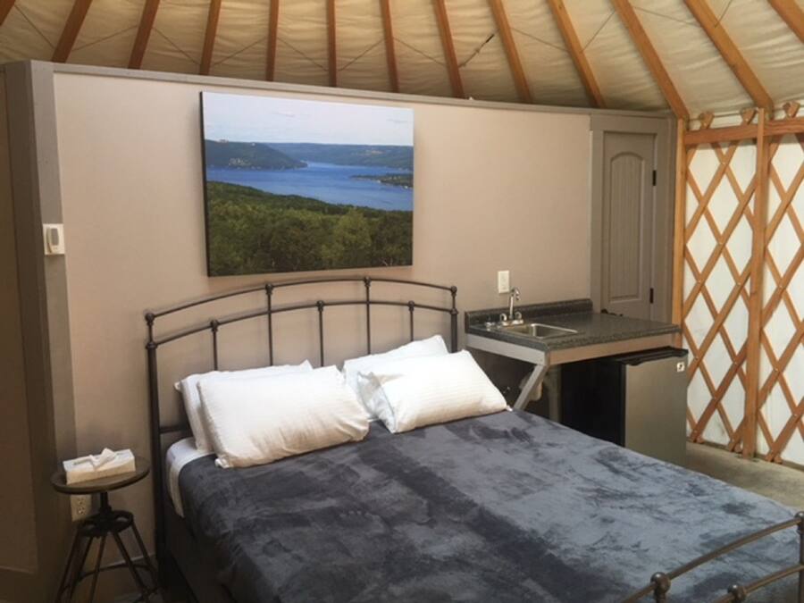 A bedroom with a bed, a small table, and a painting of a landscape.