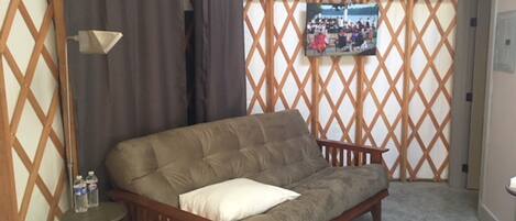 A cozy room with a wooden sofa, a small table with bottles, and a patterned rug.
