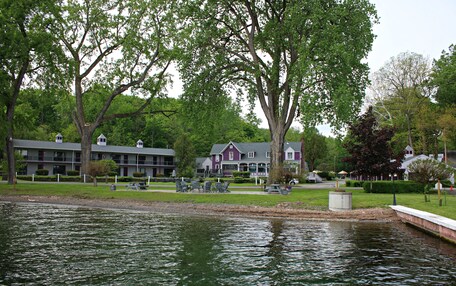 A lakeside hotel with a dining area, outdoor seating, and a view of the water.