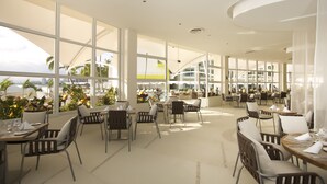 A spacious indoor dining area with large windows, modern furniture, and a view of the cityscape. - The Hacienda at Krystal Grand Puerto Vallarta (Puerto Vallarta)