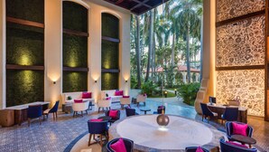 A spacious indoor area with a round table and chairs, a seating area with couches and chairs, and a view of palm trees outside. - The Hacienda at Krystal Grand Puerto Vallarta (Puerto Vallarta)