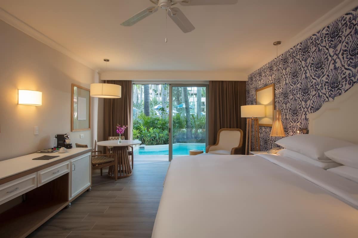 Une chambre d’hôtel équipée d’un lit, d’un bureau, d’une chaise et offrant une vue sur une piscine.