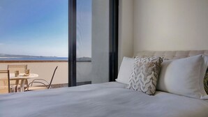 A hotel room with a large bed, a view of the sea, and a balcony with a table and chairs. - Villa Vegas by Cabo Platinum (Cabo San Lucas)