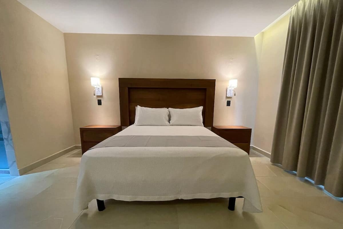 A hotel room with a large bed, two bedside tables, and a headboard.
