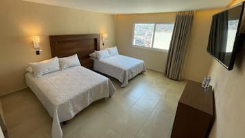 Habitación de hotel con dos camas, un televisor y una ventana con vistas.