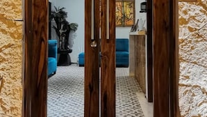 Een houten dubbele deur met een ruit, geplaatst tegen een ruwe stenen muur.