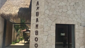 Een hotel genaamd "CASABAMBOO" met een stenen gevel en rieten dak.