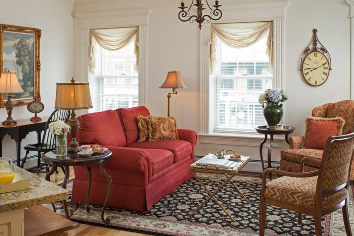 A living room with a red sofa, a patterned rug, and a chandelier.