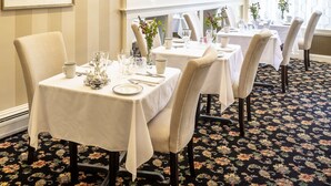A dining area with tables set for service, a chandelier, and a framed artwork on the wall. - Belfast Bay Inn (Belfast)