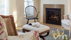 A cozy living room with a fireplace, a wooden bench, and two chairs. - Belfast Bay Inn (Belfast)