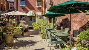 A patio area with outdoor seating and umbrellas, surrounded by brick buildings and potted plants. - Belfast Bay Inn (Belfast)