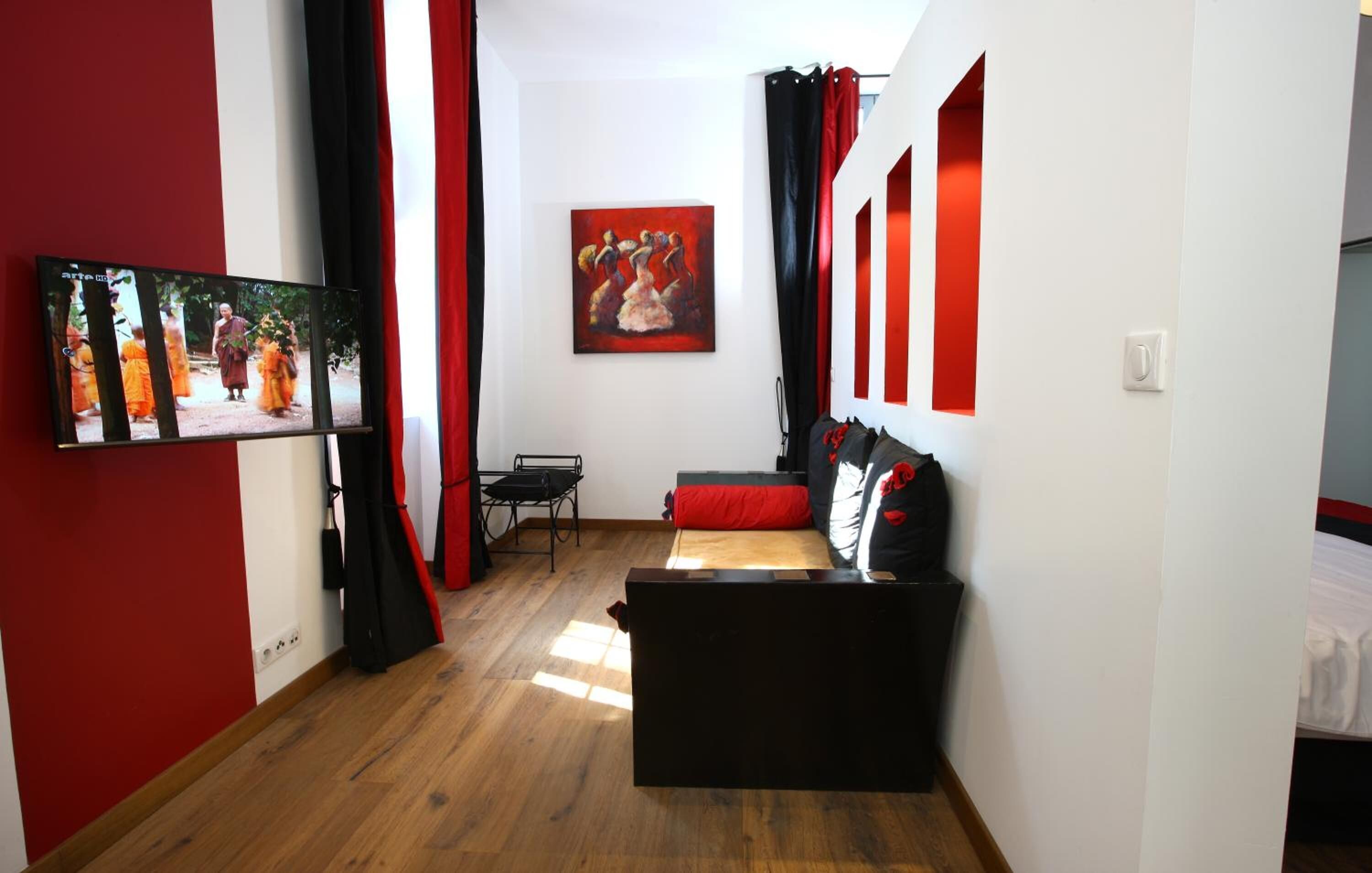A modern room with a black sofa, a small table, and a painting on the wall.