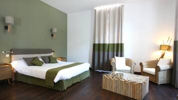 Een hotelkamer met een bed, een stoel, een salontafel en een gordijn.