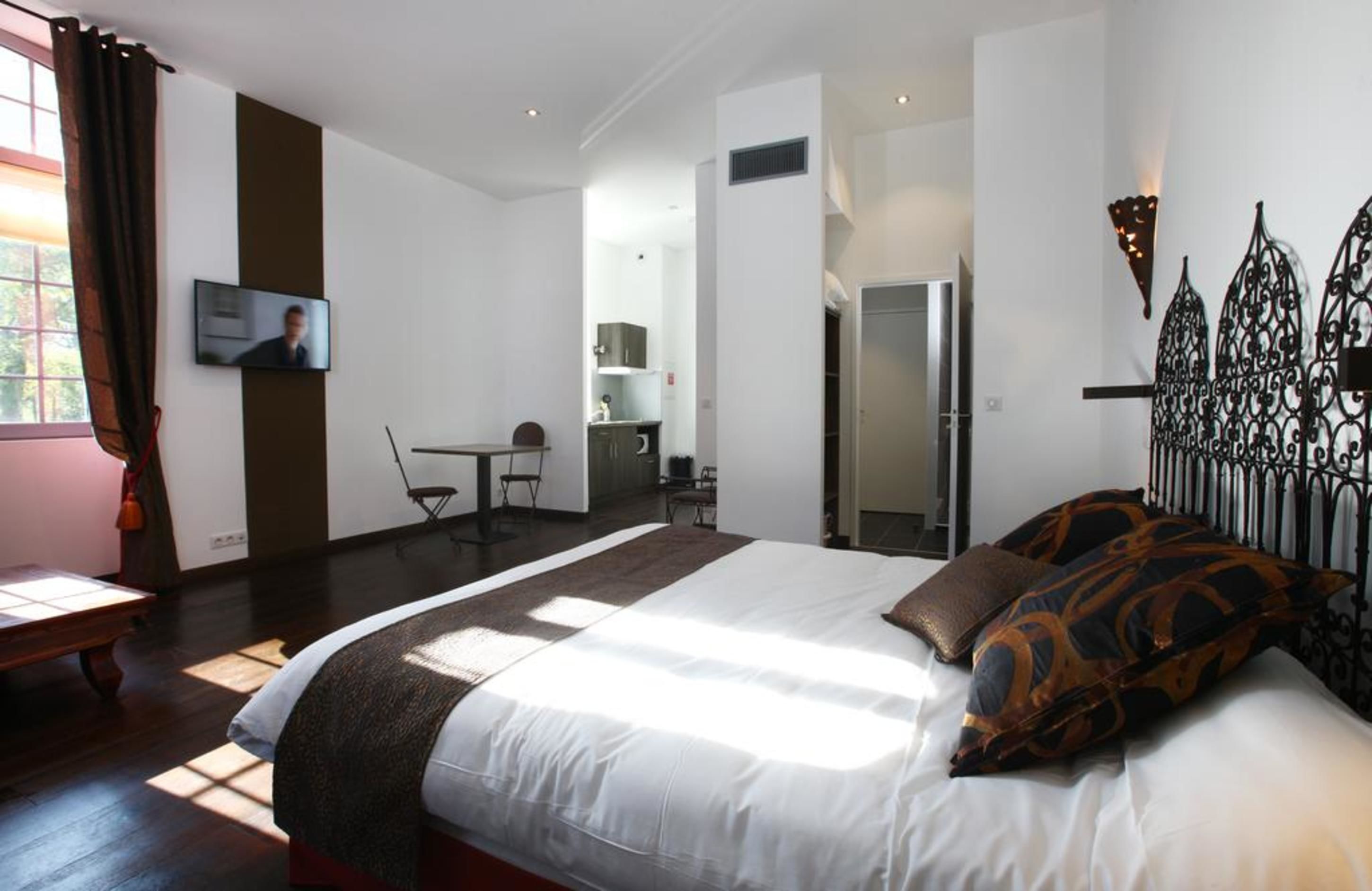 Una habitación de hotel con una cama grande, un escritorio y un televisor en la pared.