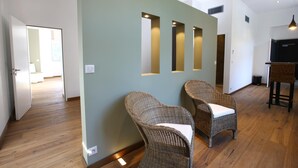 Een modern interieur met rieten stoelen, een houten vloer en inbouwverlichting in een muur.