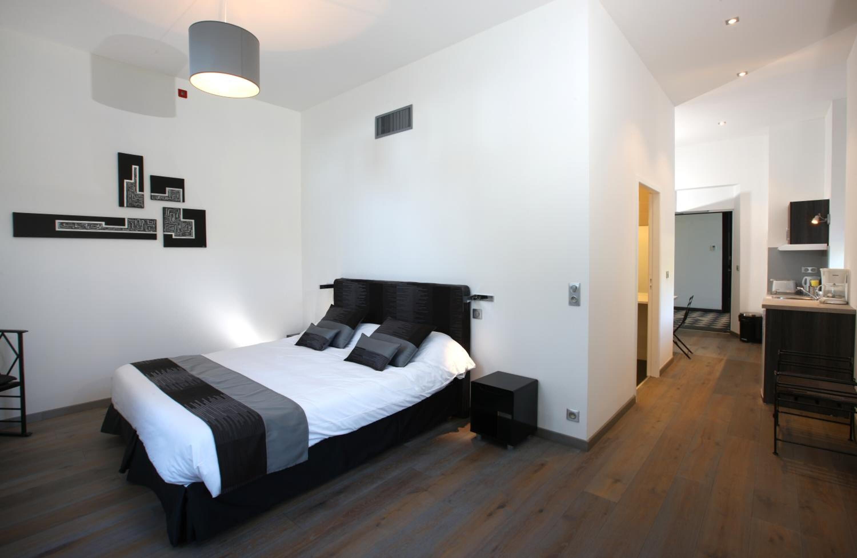 A modern bedroom with a large bed, bedside tables, a lamp, and a small desk with a chair.