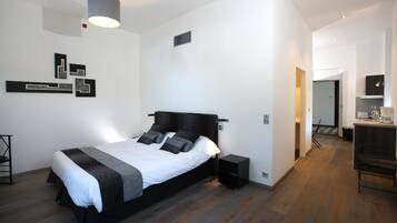 A modern bedroom with a large bed, bedside tables, a lamp, and a small desk with a chair.