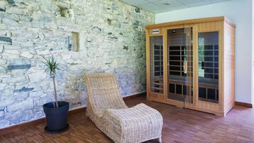 A stone wall, a wicker chair, and a wooden cabinet with glass doors.