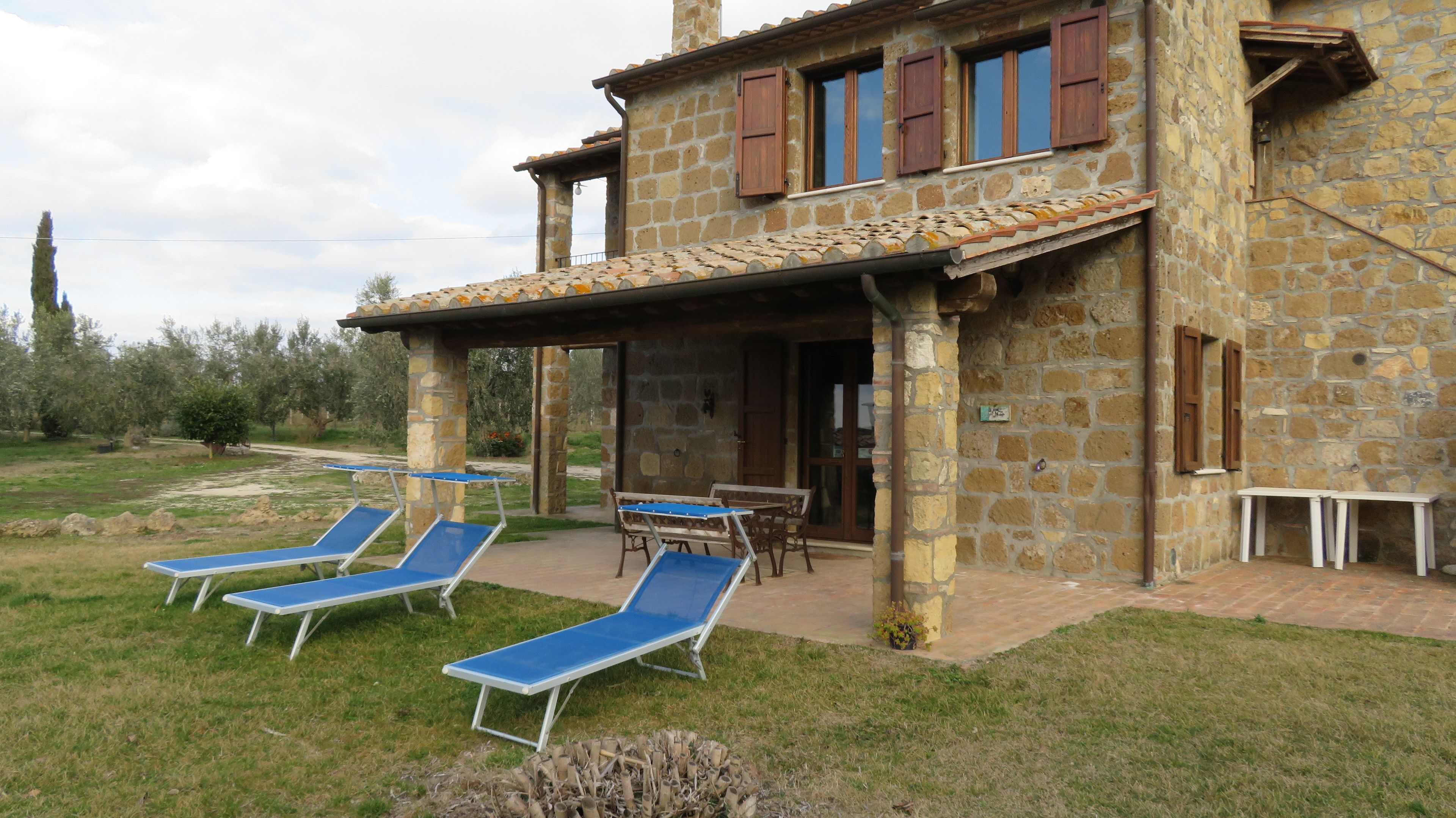 A stone building with a covered patio, outdoor seating, and lounge chairs.