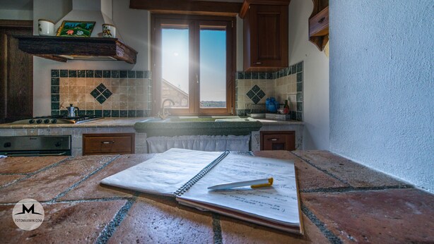 A kitchen with a tiled backsplash, wooden cabinets, a stove, and a window with a view. - Agriturismo Le Sorgenti (Pitigliano)