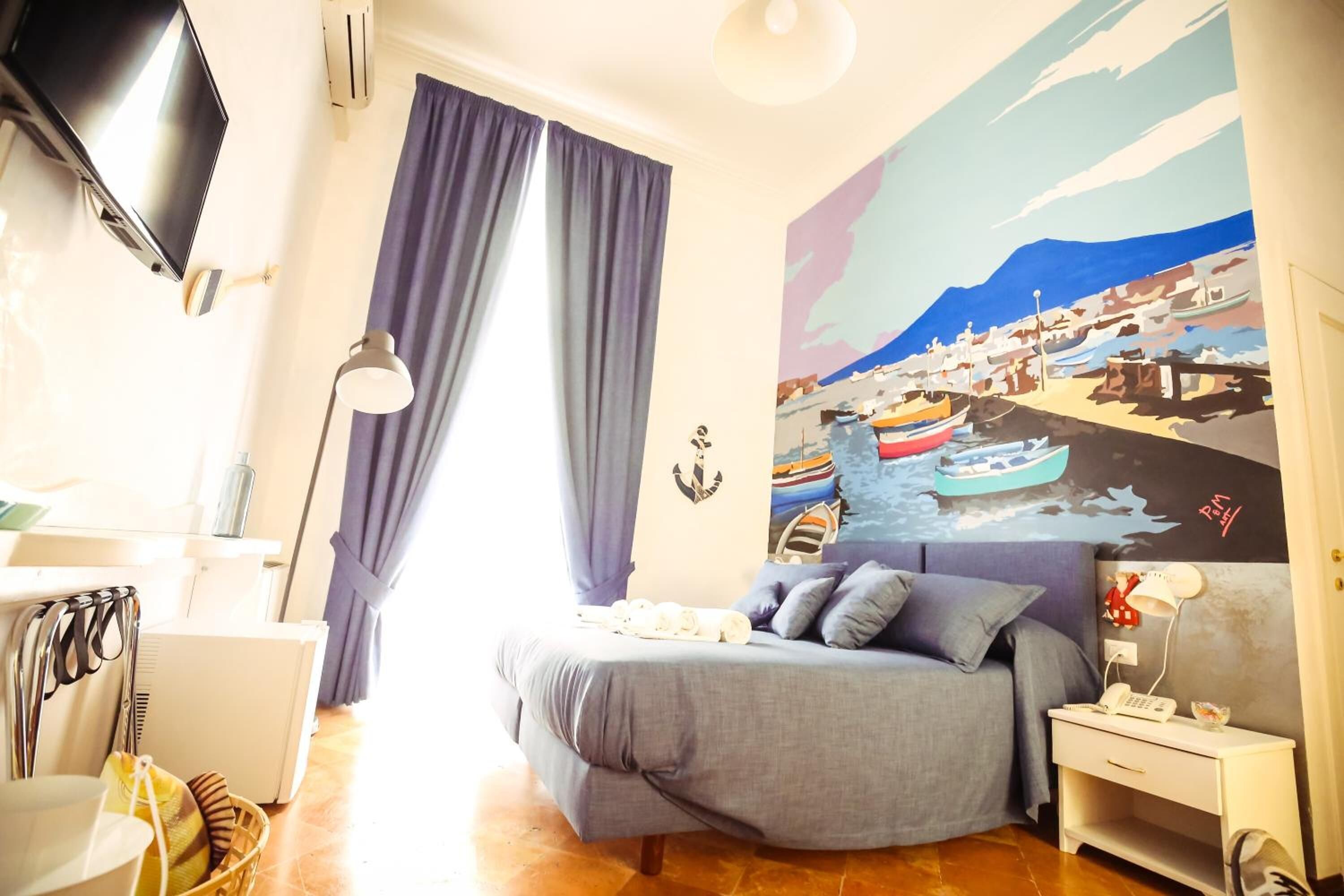 Una camera da letto con un letto, una scrivania, una sedia, una lampada e un quadro appeso al muro.