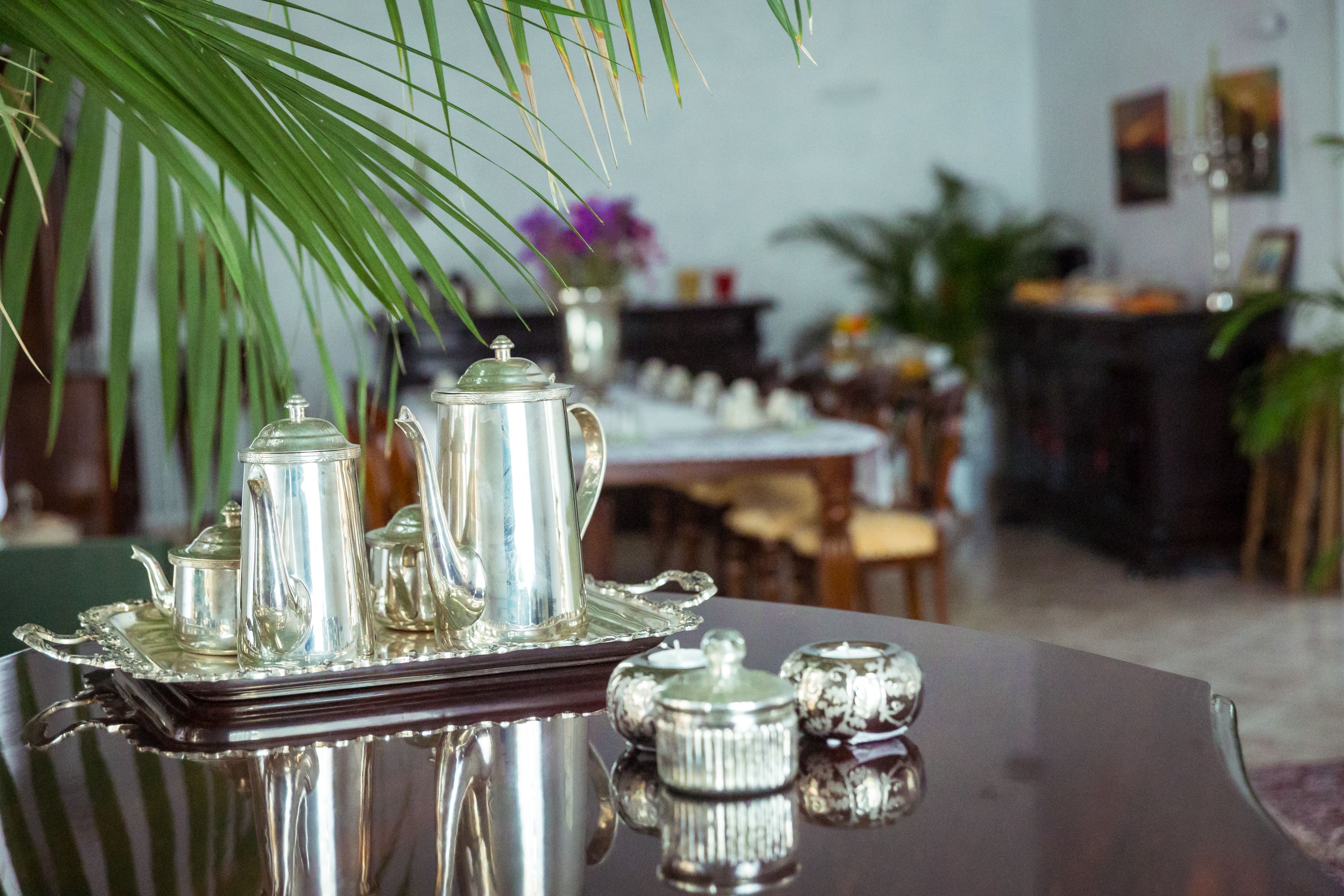 Une table à manger agrémentée d’un service à thé en argent et d’un plateau décoratif.