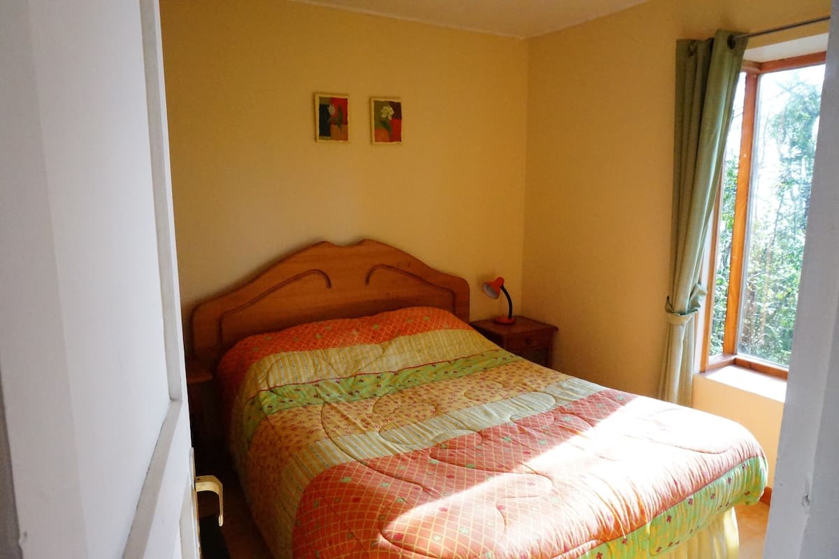 Ein Schlafzimmer mit einem hölzernen Bett, einem Nachttisch und einem Fenster mit Vorhängen.