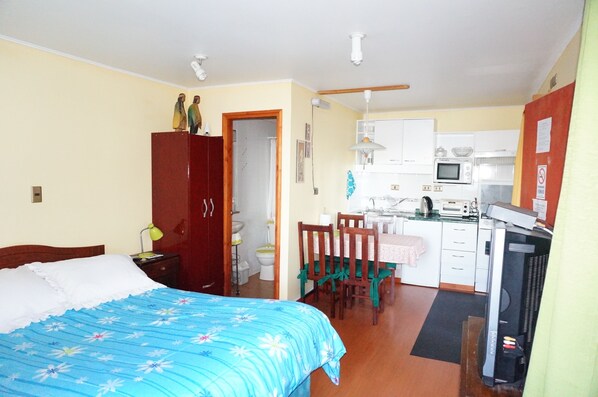 Un dormitorio con cama, escritorio y kitchenette.