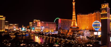 A nighttime cityscape with illuminated buildings, including a prominent tower and a large hotel with a distinctive dome.