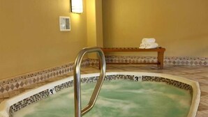 A hot tub with a metal ladder, a bench with towels, and a tiled border. - Jockey Club Suites (Las Vegas)